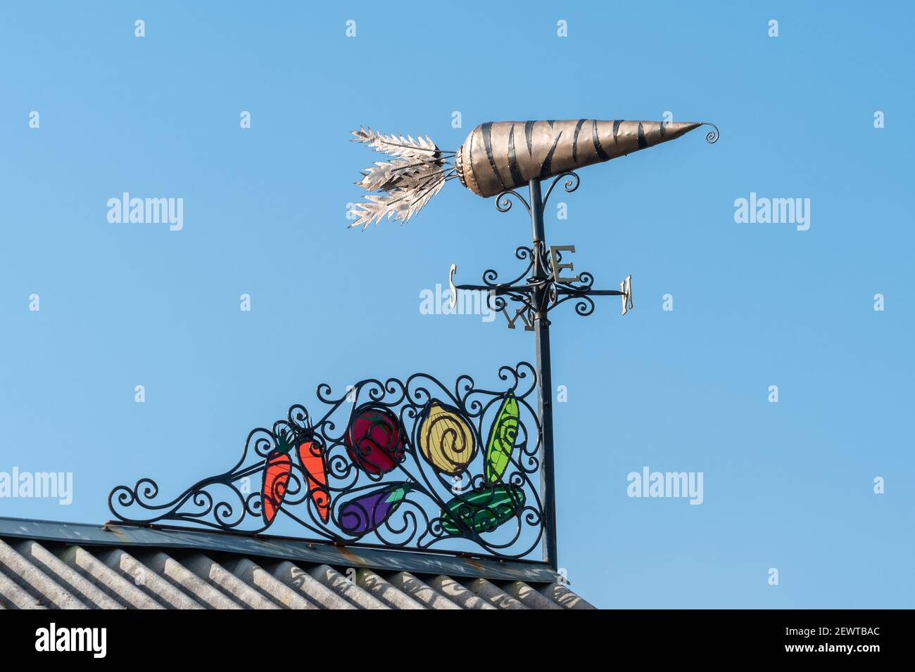 Karotte geformte Wetterfahne mit bunten Glasmalerei Funktion, Kunstinstallation auf dem Dach der Zuteilung Schuppen in der Kirche Crookham, Hampshire, England, Großbritannien Stockfoto