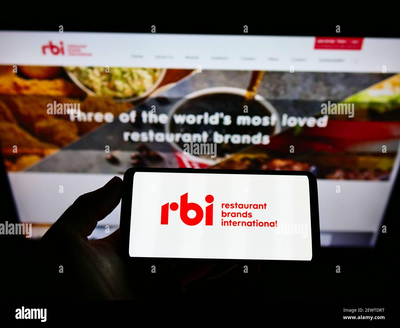 Person, die Mobiltelefon mit Logo des Fast-Food-Unternehmens Restaurant Brands International Inc. (RBI) auf dem Bildschirm mit Website hält. Konzentrieren Sie sich auf die Telefonanzeige. Stockfoto