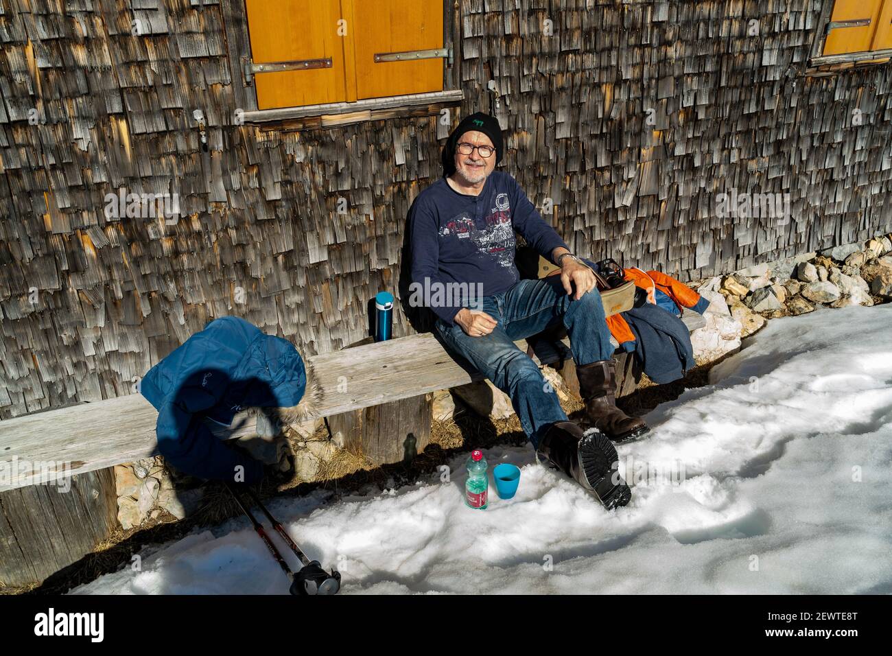 Pause auf der Bank an einer geschindelten Alphütte. Pause auf der Bank bei einer Schindelhütte. Wintersport in Österreichs verschneiten alpen. Schneeschuh Stockfoto