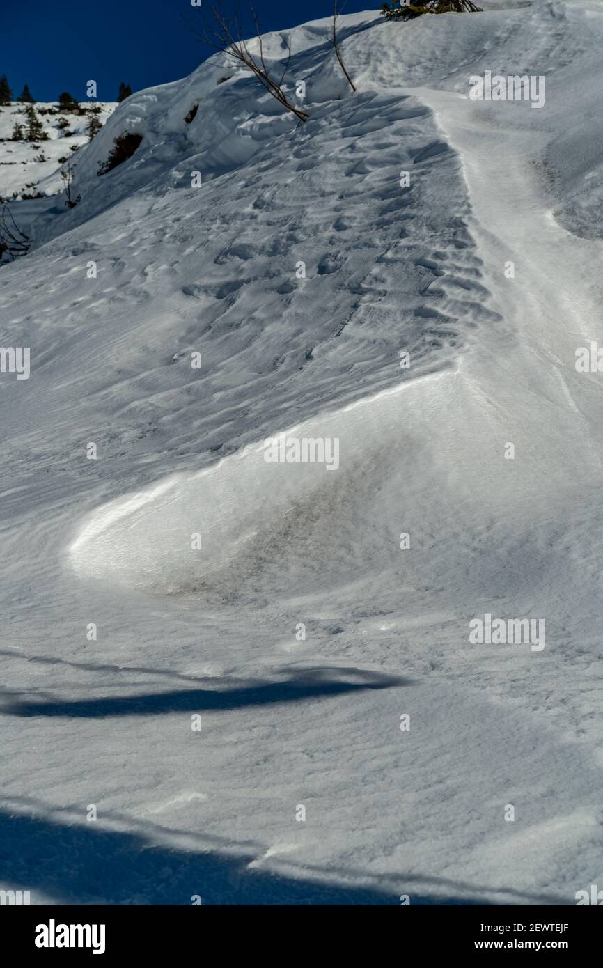 Interessante Schneeoberflächen und Formen, Bäumen und Bergen. Winterwunderland mit interessanten Schneeflächen und Formen, Bäumen und österreichischem Berg Stockfoto