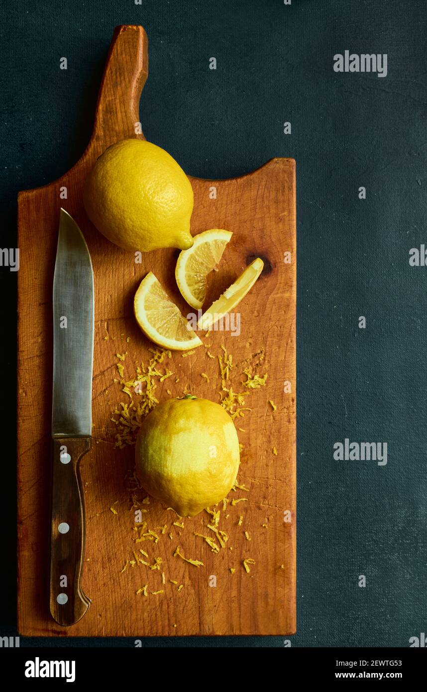 Frische Zitronen und ein Küchenmesser auf einem Holzbrett, Draufsicht Stockfoto