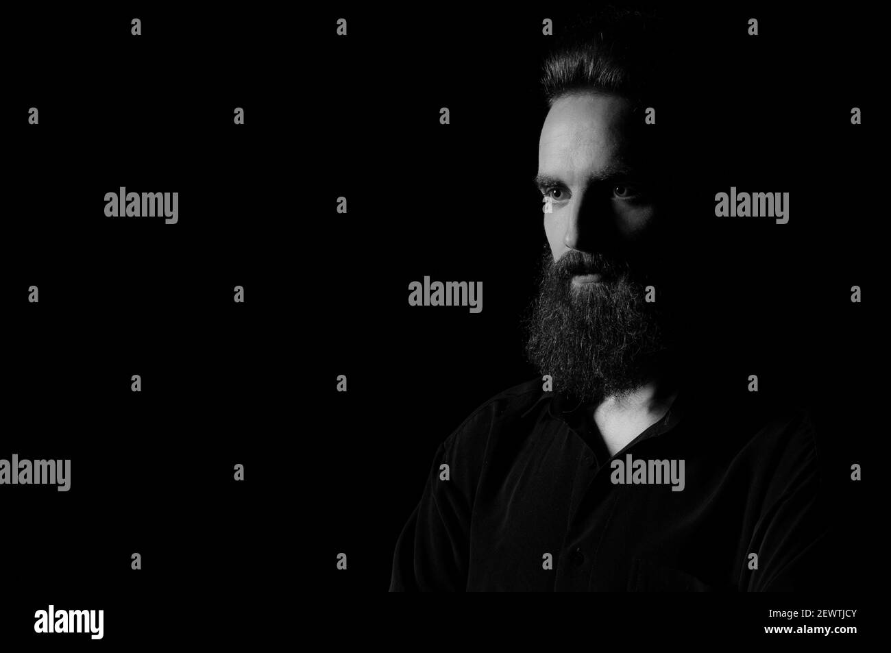 Porträt eines bärtigen Mannes in einem Studio-Umgebung vor einem schwarzen Hintergrund mit dramatischen Low-Key-Lichter. Stockfoto
