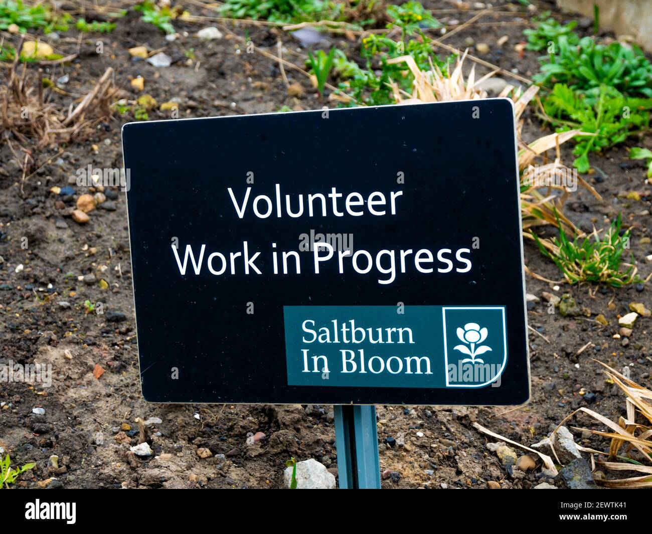Ein kleines Schild Freiwillige Arbeit in Arbeit auf der oberen Promenade in Saltburn by the Sea vollständig von Freiwilligen gepflegt Gärtner Stockfoto