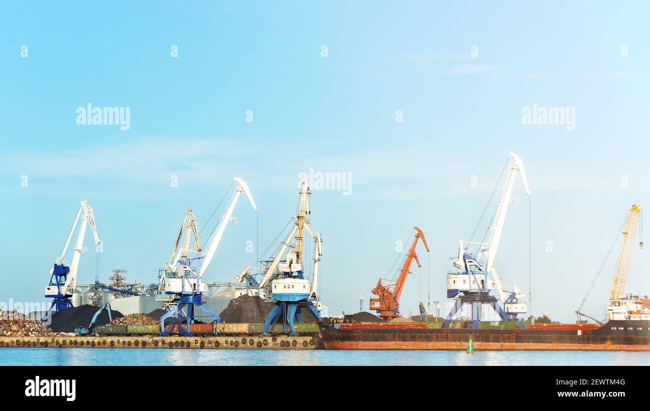 Arbeitskrane mit Frachtschiff, Lastkahn auf Verladung in der Werft am Sonnentag, Toning, selektiver Fokus Stockfoto