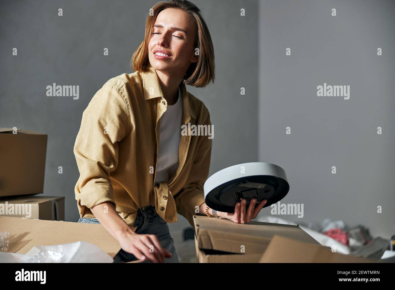 Frau mit einer Wanduhr, die in einem unmöblierten Zimmer sitzt Stockfoto