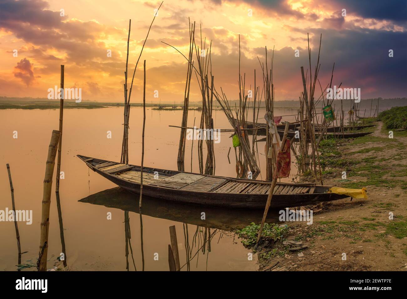 Holzboote Reihen sich am Flussufer mit launischen Sonnenuntergang Himmel in einem ländlichen Bezirk in West Bengalen, Indien Stockfoto