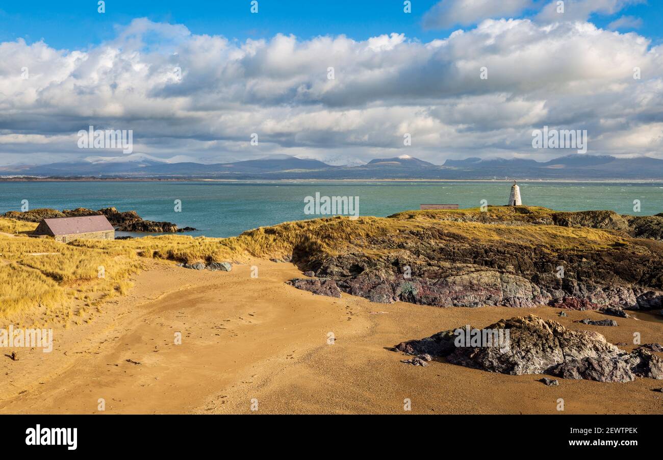 Ein Blick auf Twr Bach und die schneebedeckten Snowdonia Berge über Porth Twr Mawr auf LLanddwyn Island, Anglesey, Wales Stockfoto