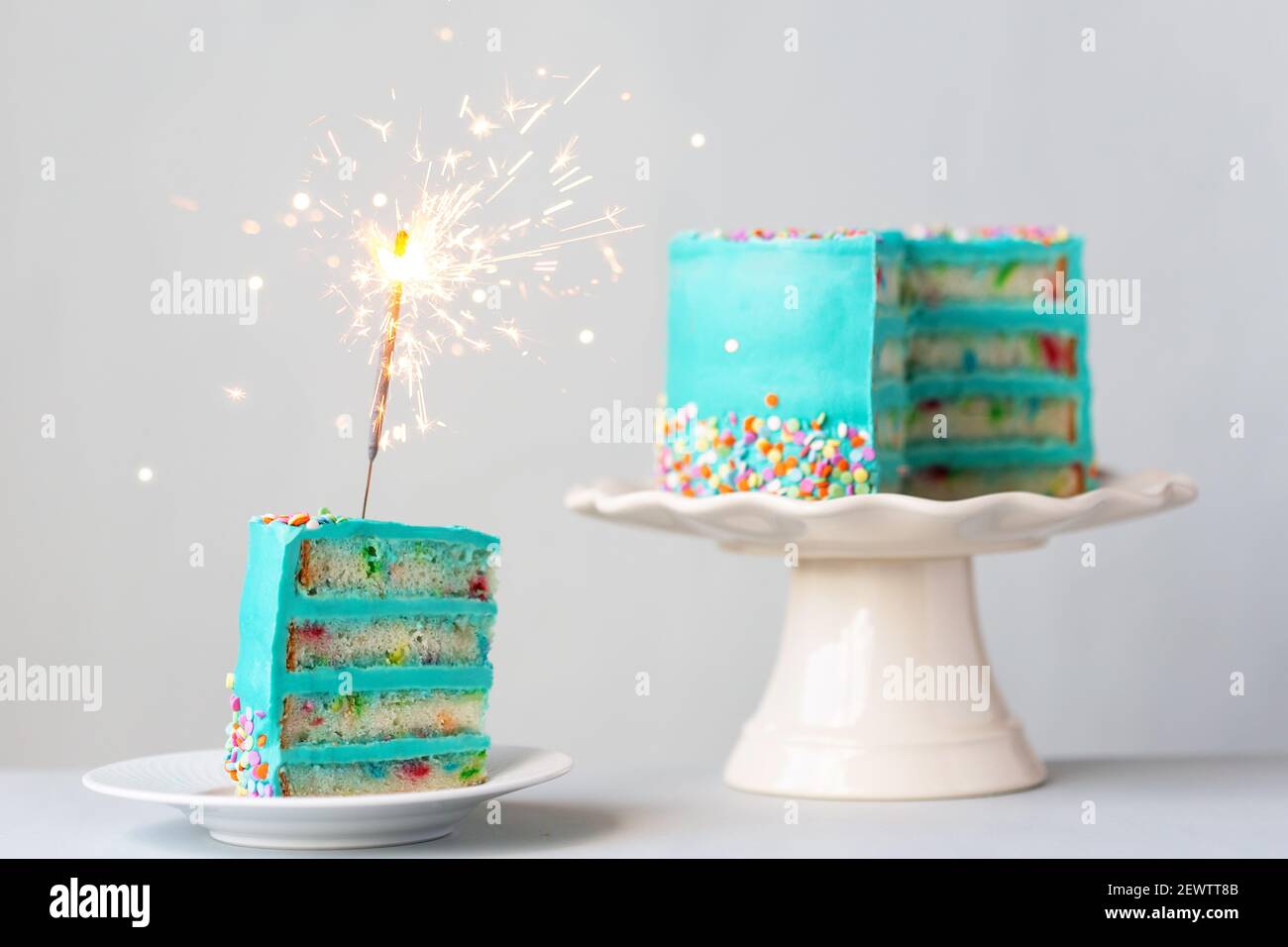 Scheibe Geburtstagskuchen mit türkisfarbenem Zuckerguss und einem Wunderkerze Stockfoto
