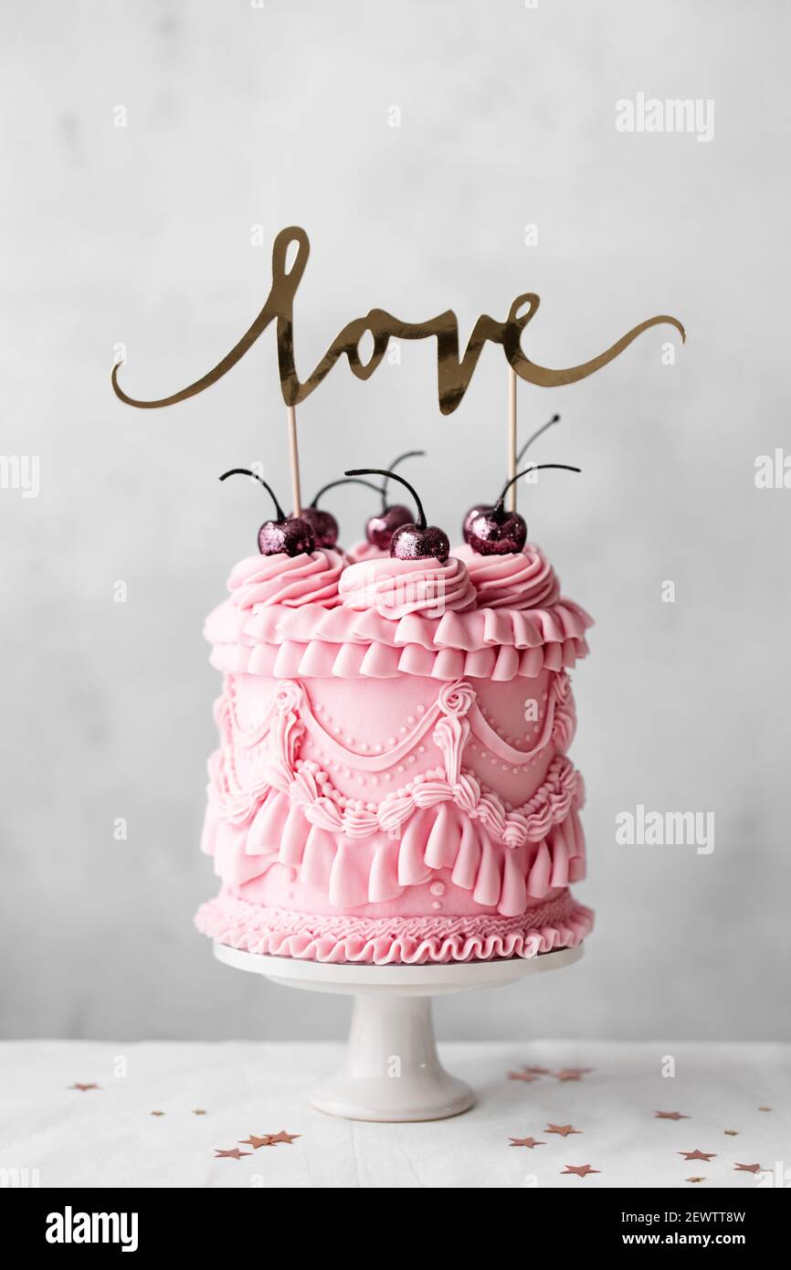 Vintage Feier Kuchen mit pastellrosa vintage Buttercreme Paspeln und Banner mit Liebe Stockfoto