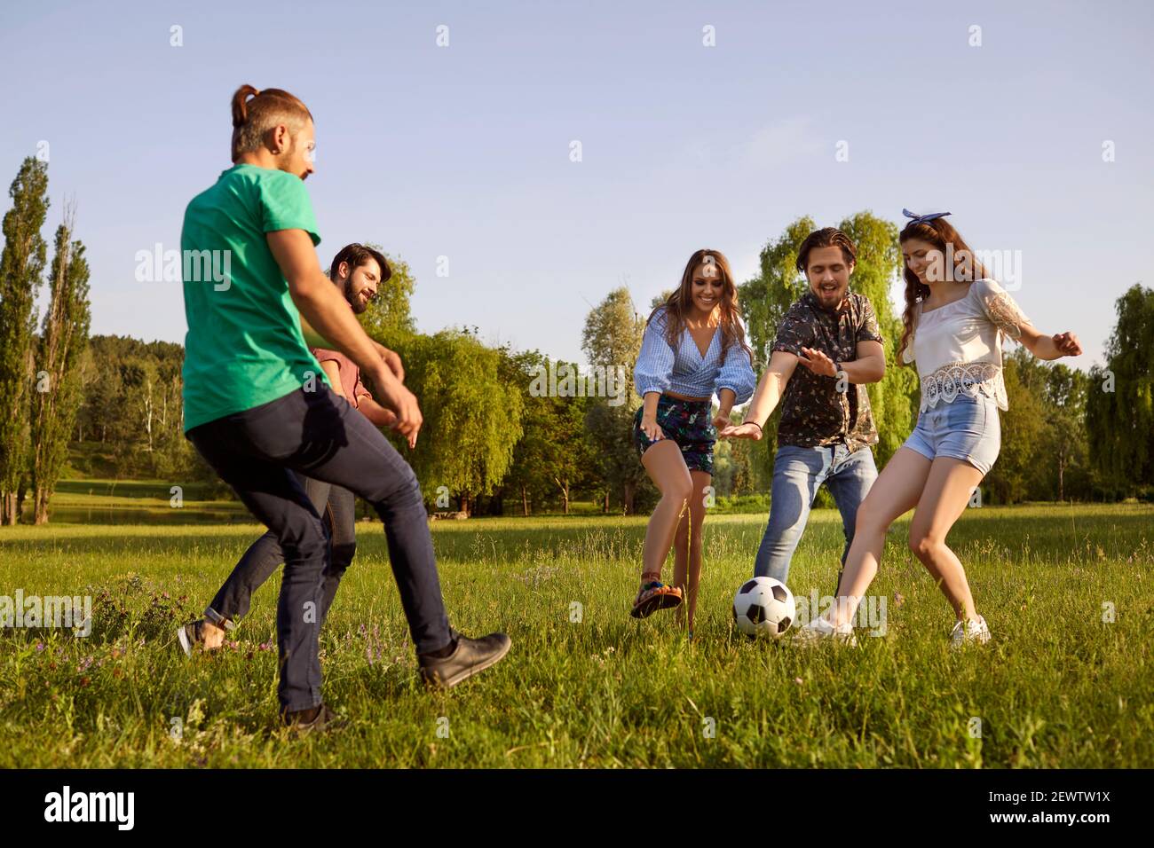 Glückliche Freunde haben Spaß beim aktiven Spielen im Park auf der grünen Wiese. Stockfoto