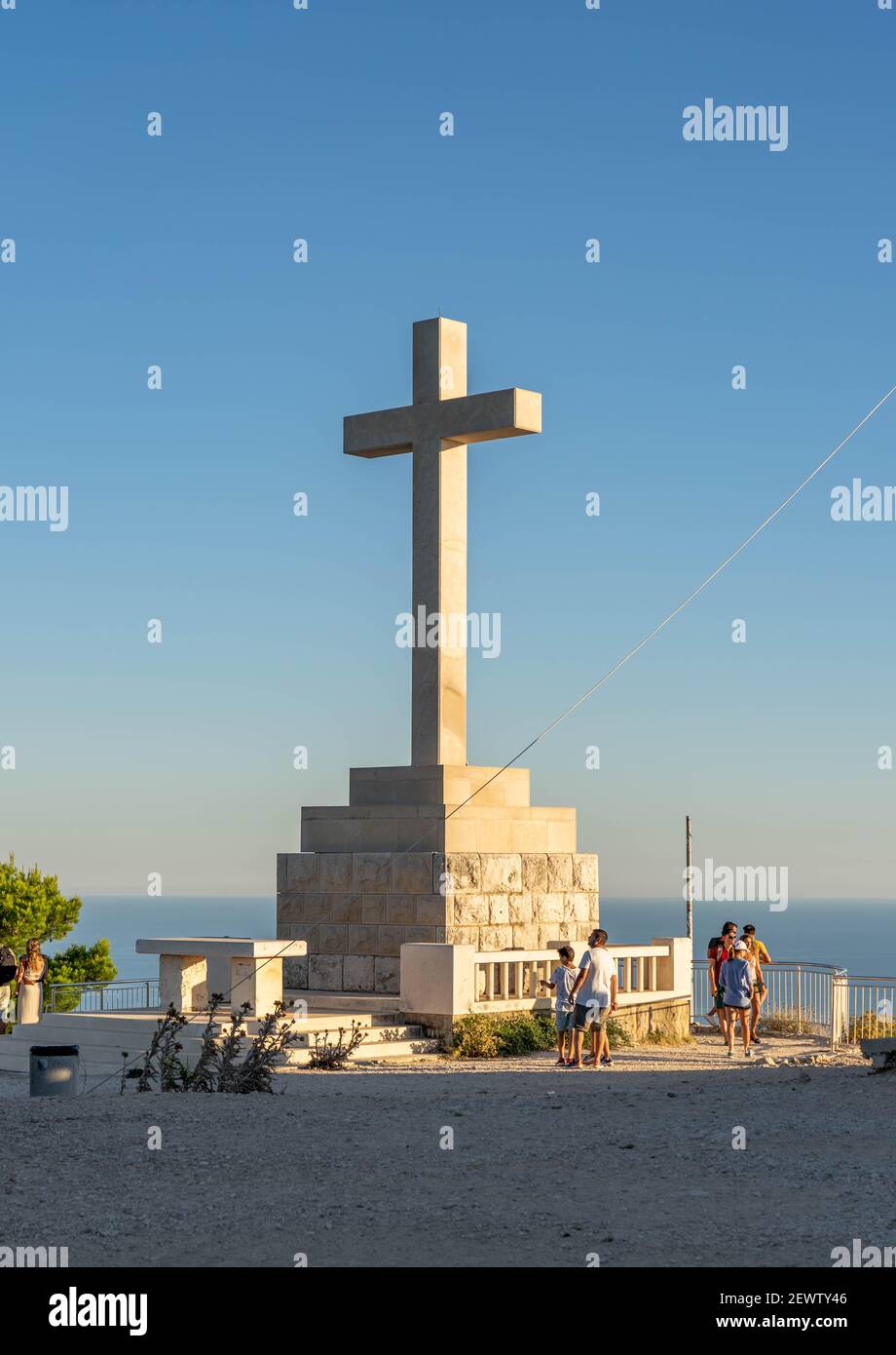 Dubrovnik, Kroatien - Aug 21, 2020: Touristen auf dem Gipfel des Berges SRD mit weißem Kreuz in Sonnenuntergang Stockfoto