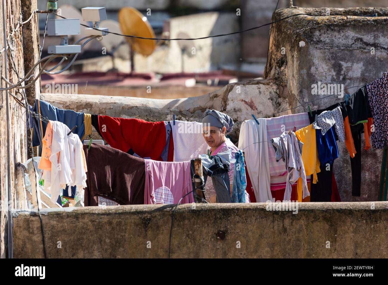 Porträt einer einheimischen Frau, die Kleidung an einer Wäscheleine auf einer Dachterrasse in der Medina von Fes, Marokko, aufhängt Stockfoto