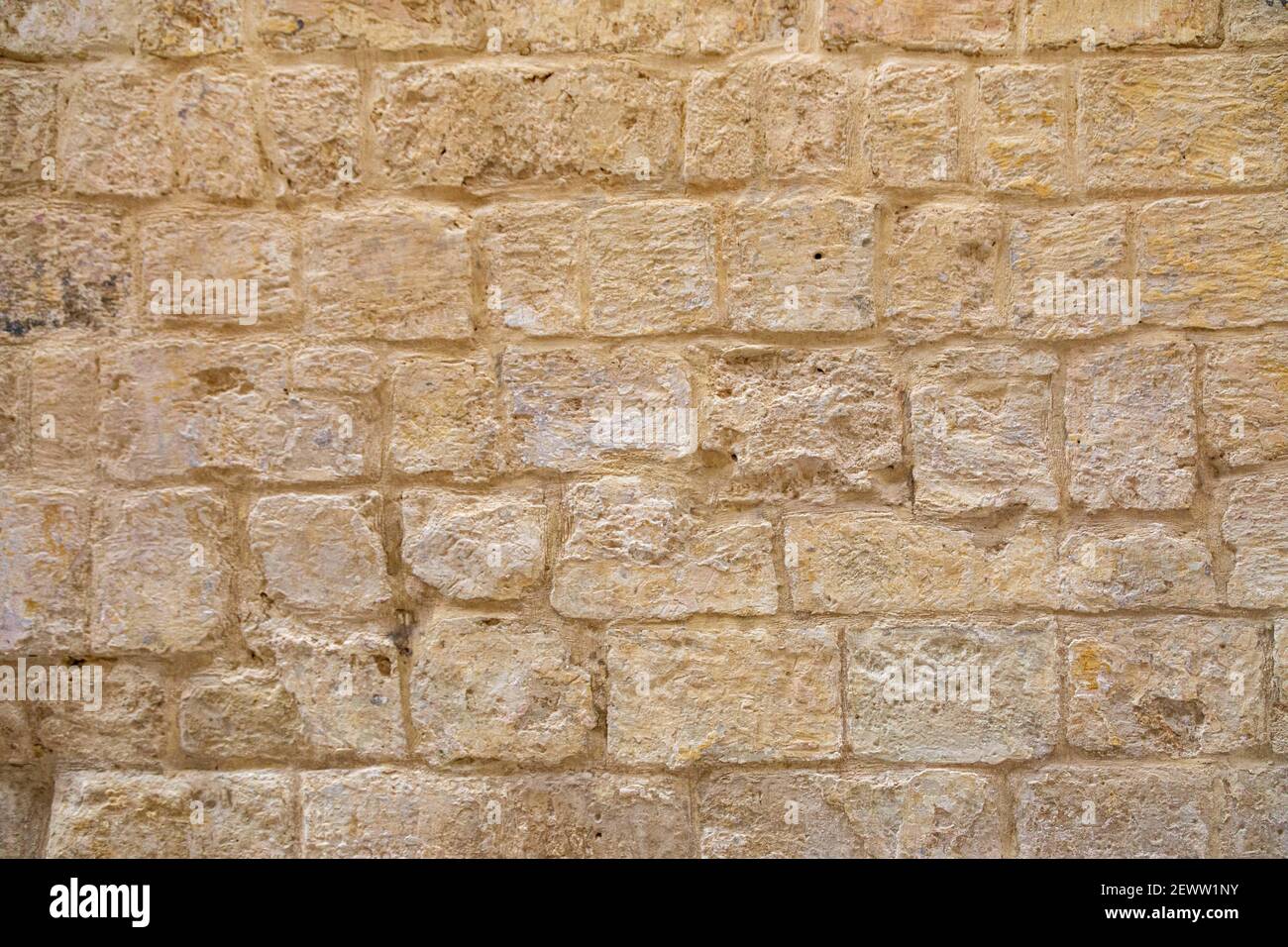 Verfallene, strukturierte, gealterte, goldgelbe Steinmauer in Ziegelform Stockfoto