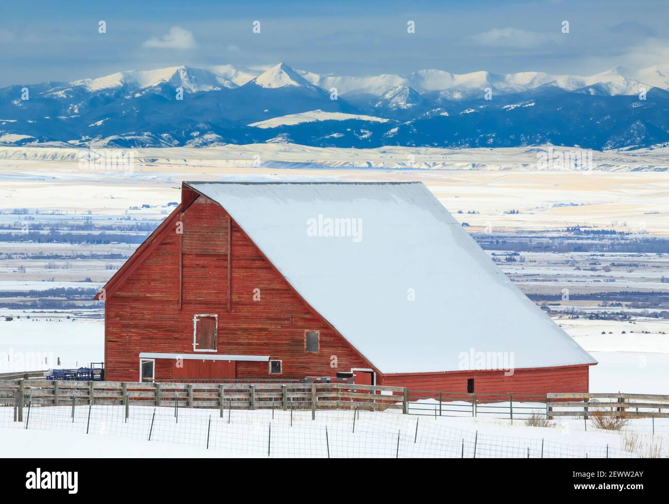 Rote Scheune und weit entfernte Tabakwurzelberge im Winter in der Nähe von belgrad, montana Stockfoto