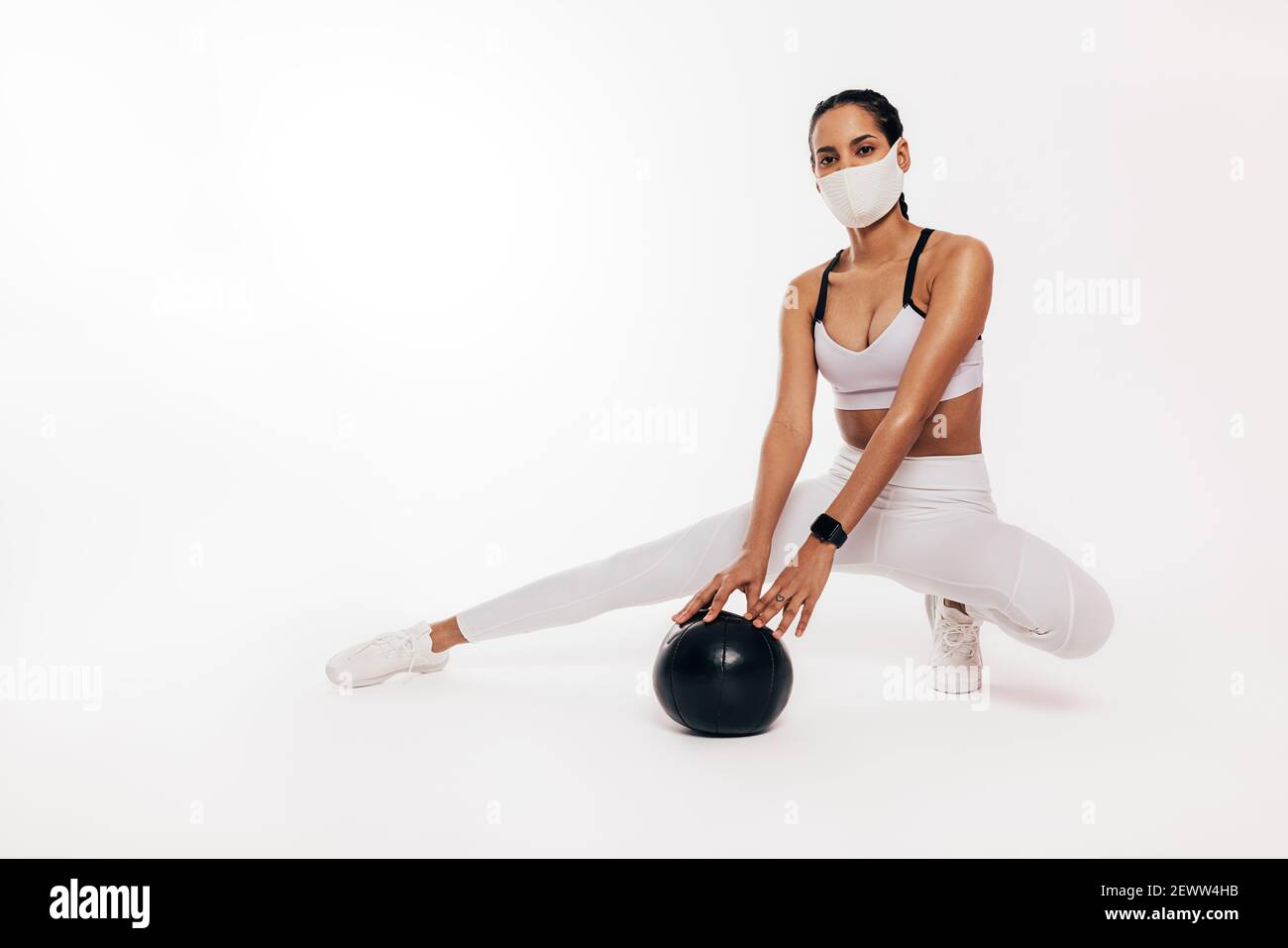 Mixed Race Frau mit Gesichtsmaske sitzt in einem Studio Stockfoto
