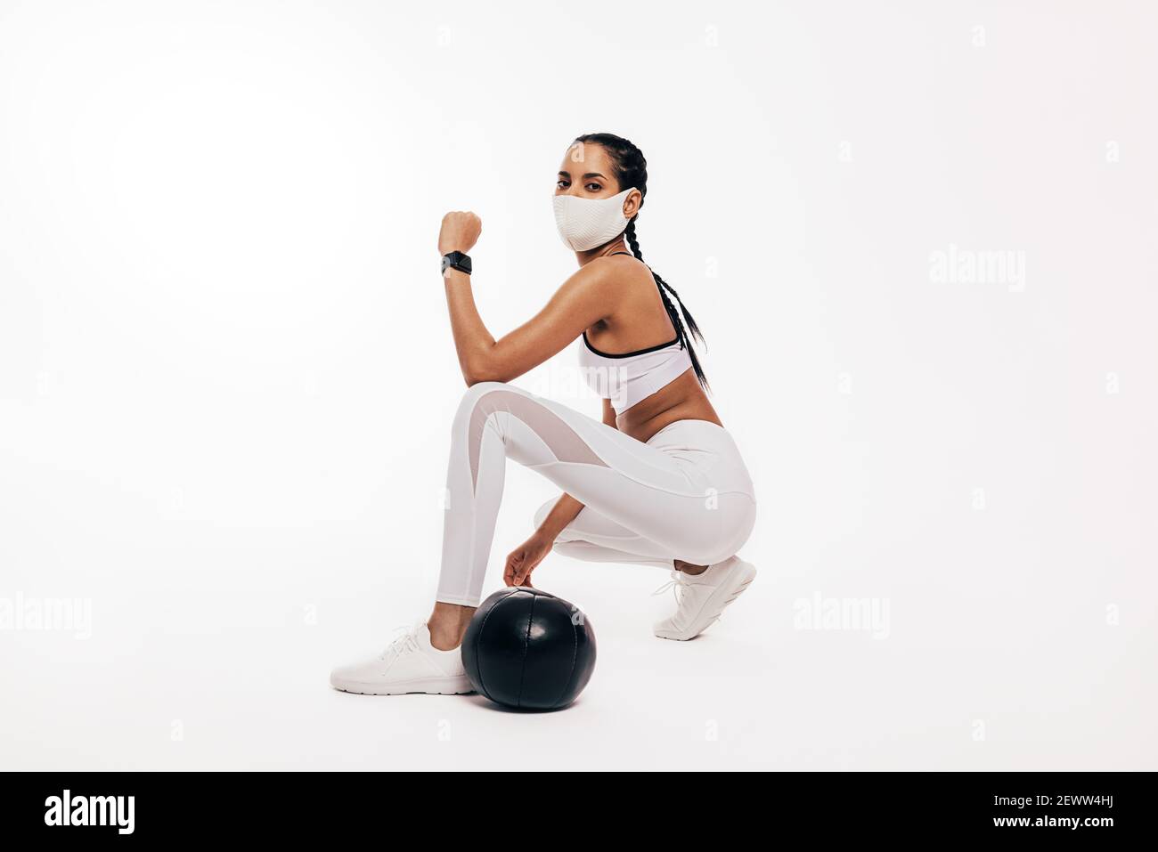 Junge Frau mit Gesichtsmaske tun Fitness-Training mit einem Medizinball Stockfoto