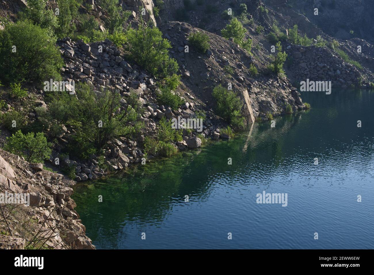 Felsenufer des Schwarzen Sees in der Nähe des Dorfes Mygia in der Ukraine. See auf dem Gelände eines überfluteten Granitsteinbruchs. Stockfoto