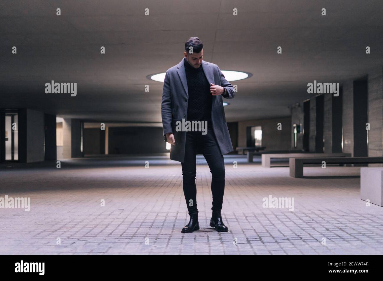Hübscher junger Geschäftsmann, der seinen Mantel aufhängt und steht. Stockfoto