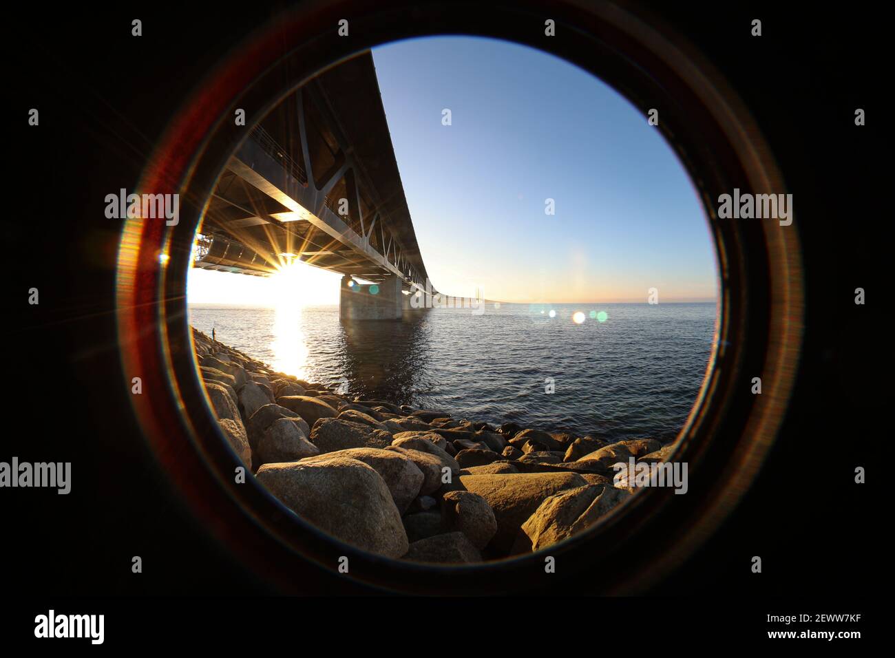 Sonne gesehen durch die Oresundbrücke am Aussichtspunkt bei Limhamn, Schweden, im Februar 2021. Weitwinkel, klarer Himmel, Brücke von links nach Stockfoto
