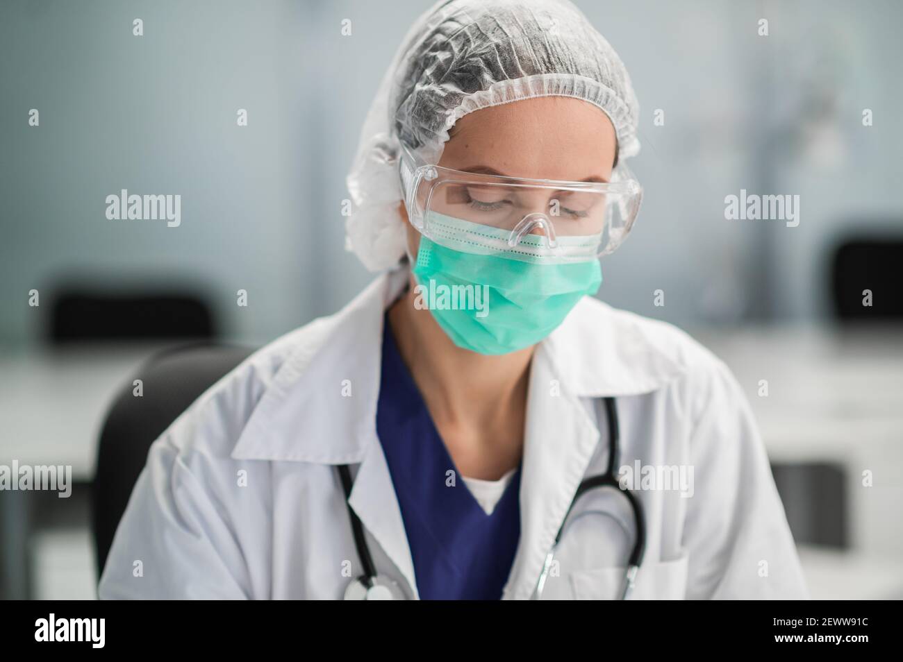 Porträt einer jungen Ärztin in einer Schutzmaske Und Cap in seinem Büro Stockfoto