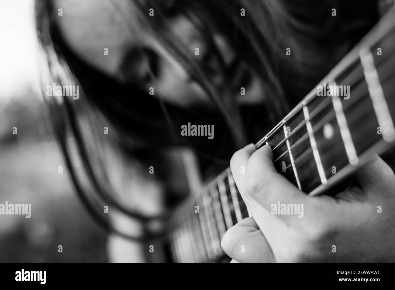 Mädchen spielt akustische Gitarre – Finger auf den Saiten. Schwarzweiß-Foto. Stockfoto