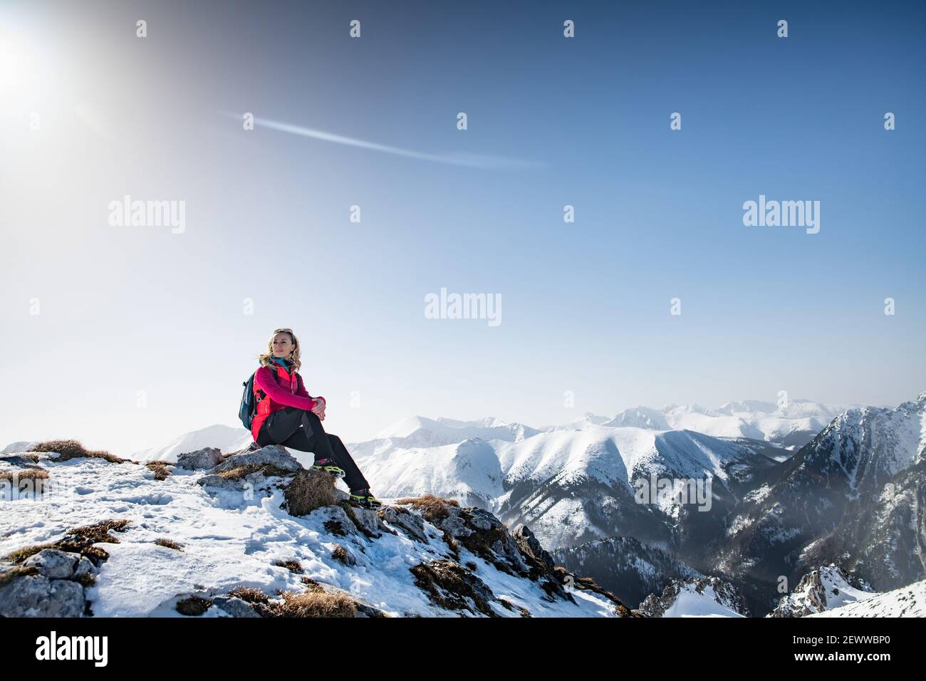 Blonde Frau Touristen sitzen auf dem Felsen. Winterwanderszene. Stockfoto
