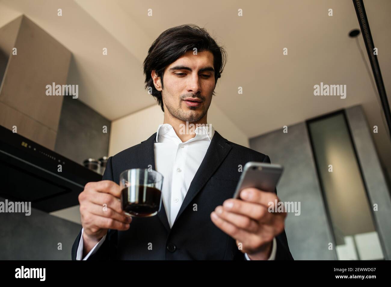 Geschäftsmann lesen Nachrichten vom Smartphone, während er einen Kaffee trinkt Zu Hause Stockfoto