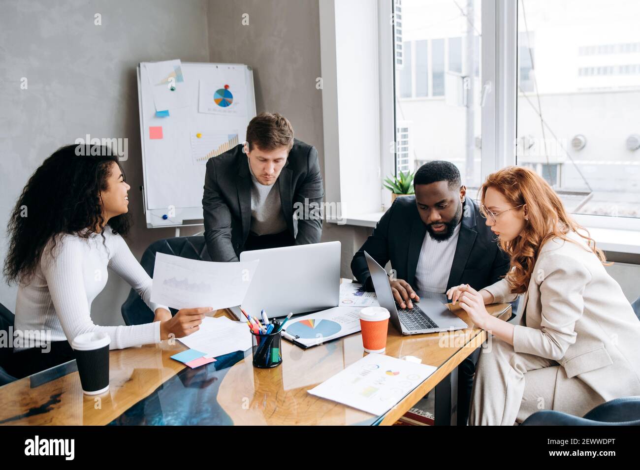Besprechung des Geschäftsteams. Gruppe von erfolgreichen Menschen, studieren Finanzgraphen und Diagramme, Brainstorming zusammen. Multiethnische Mitarbeiter diskutieren Ideen, arbeiten an einem neuen Projekt Stockfoto