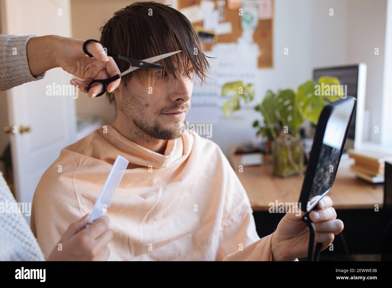 Haarschnitt zu Hause. Mann, der zu Hause Haare schneidet. Leben in einer Pandemie während der Sperrung. So schneiden Sie Ihr eigenes Haar, wenn Friseure geschlossen sind. Einfachste Selbsthaarschnitt Stockfoto