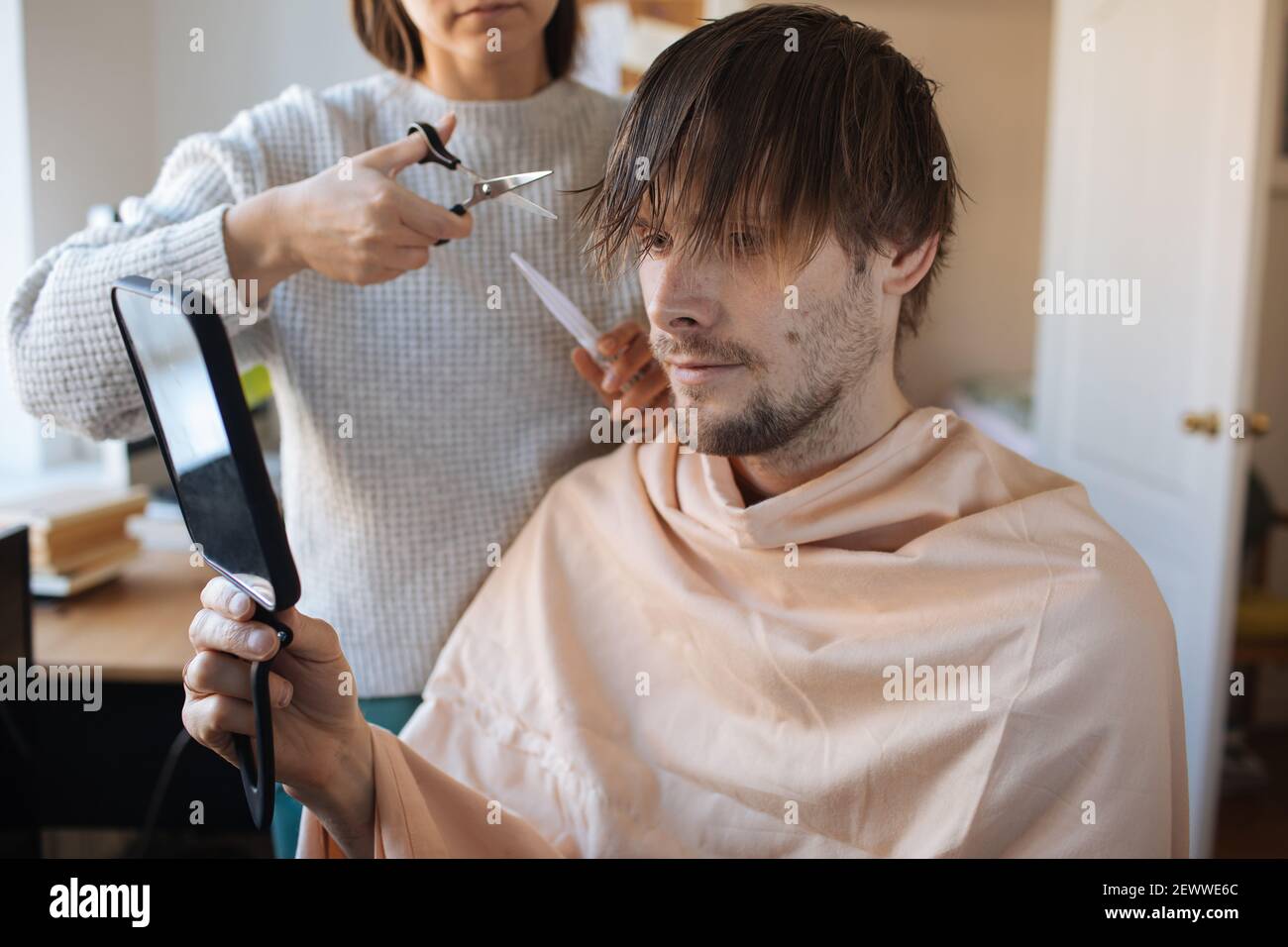 Haarschnitt zu Hause. Mann, der zu Hause Haare schneidet. Leben in einer Pandemie während der Sperrung. So schneiden Sie Ihr eigenes Haar, wenn Friseure geschlossen sind. Einfachste Selbsthaarschnitt Stockfoto