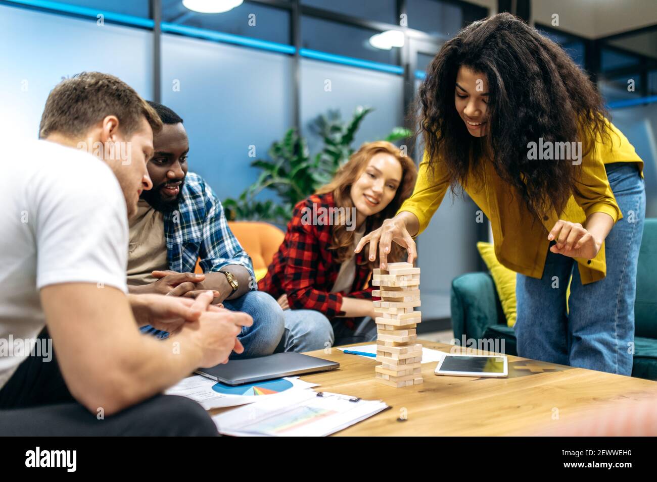 Fröhliche, freundliche Geschäftsleute, die im Büro spielen und eine Pause einlegen. Fröhliche multiethnische Mitarbeiter, die Spaß haben, sich von angespanntem Brainstorming ausruhen, von der Arbeit oder dem Studium abgelenkt sind Stockfoto