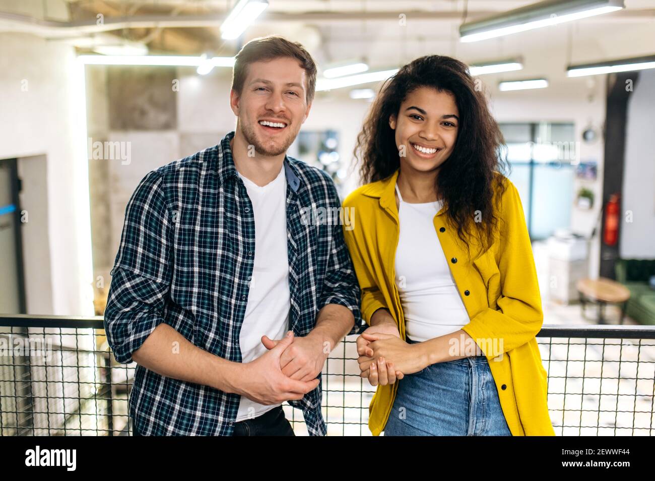 Porträt von Geschäftskollegen oder studentischen Freunden. Schöner kaukasischer Mann und schöne afroamerikanische Frau arbeiten oder studieren zusammen, Kollegen schauen lächelnd auf die Kamera Stockfoto