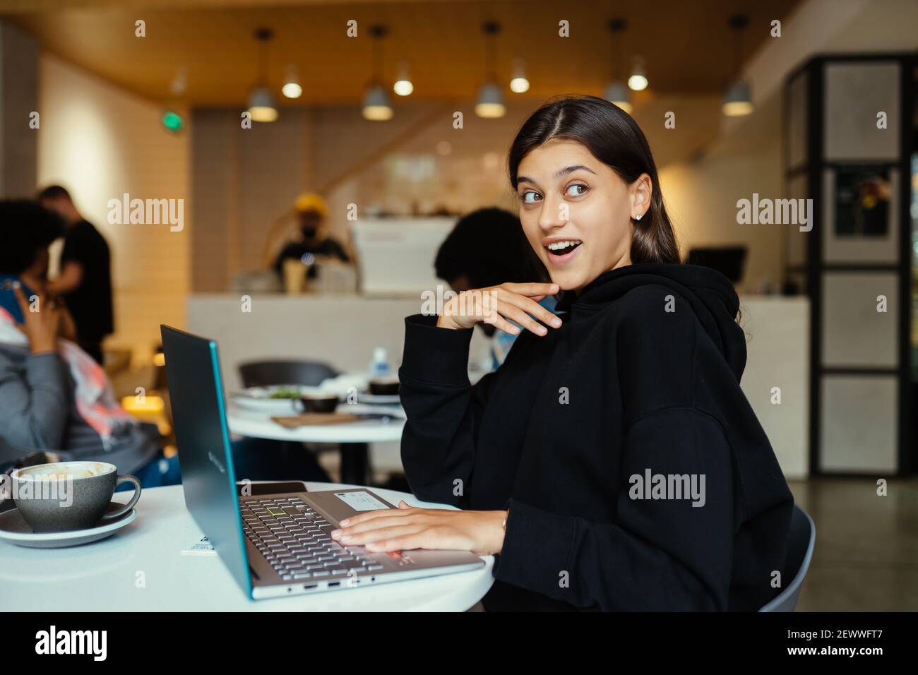 Portrait einer Studentin, die im Café mit einem Netzbuch sitzt Stockfoto