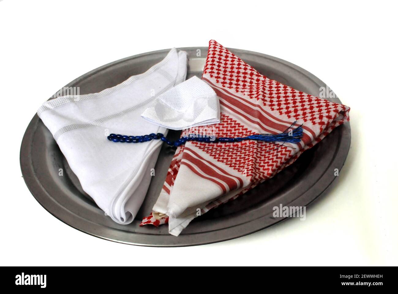Arabisches traditionelles Bekleidungszubehör genannt Shemagh, weißer Ghutrah, weiße islamische Kappe und Rosenkranz isoliert in Tablett auf weißem Hintergrund Stockfoto
