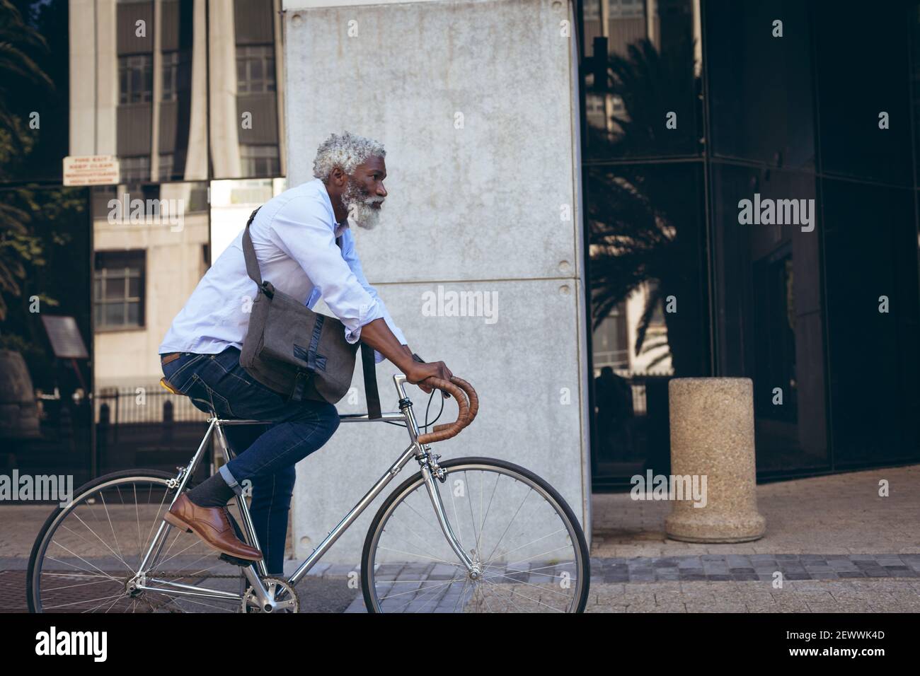 afroamerikaner älterer Mann, der Fahrrad in der Straße vorbei fährt Eingang Stockfoto