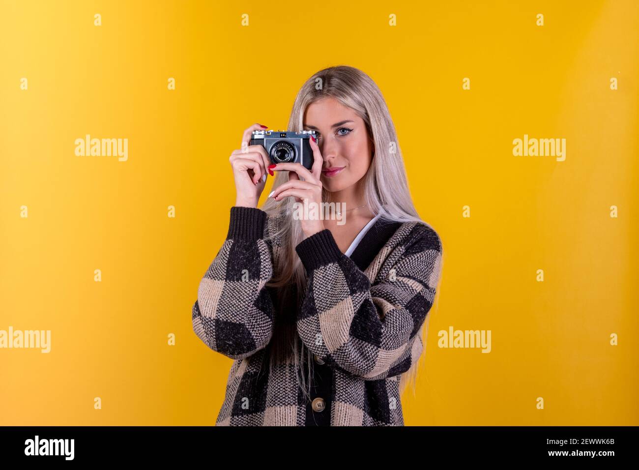 Modischer Look, schönes junges Frauenmodell mit Retro-Kamera, isoliert auf gelbem Hintergrund - Nahaufnahmporträt einer süßen Fotografin Stockfoto
