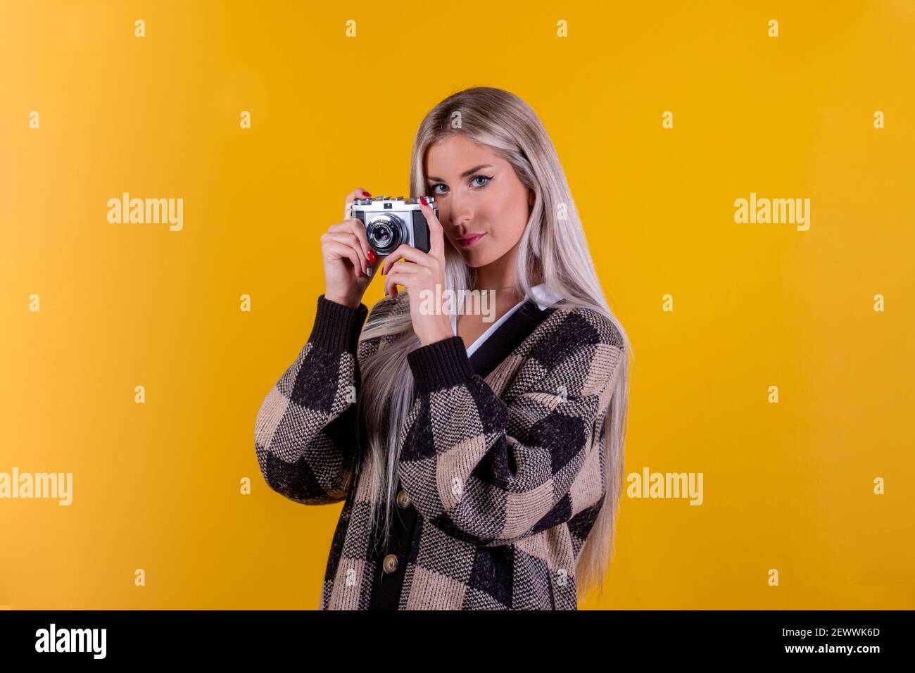 Modischer Look, schönes junges Frauenmodell mit Retro-Kamera, isoliert auf gelbem Hintergrund - Nahaufnahmeportrait einer süßen Fotografin ist tak Stockfoto
