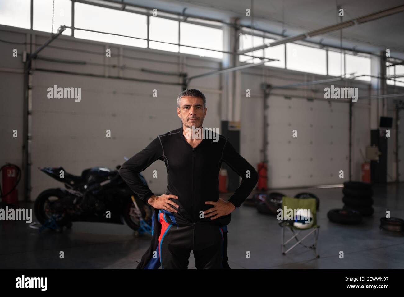 Selbstbewusster Motorradfahrer in der Garage vor dem Rennen Stockfoto