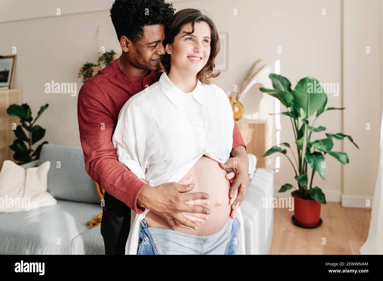 Glücklich ethnischen Mann umarmt schwangere Frau zu Hause Stockfoto