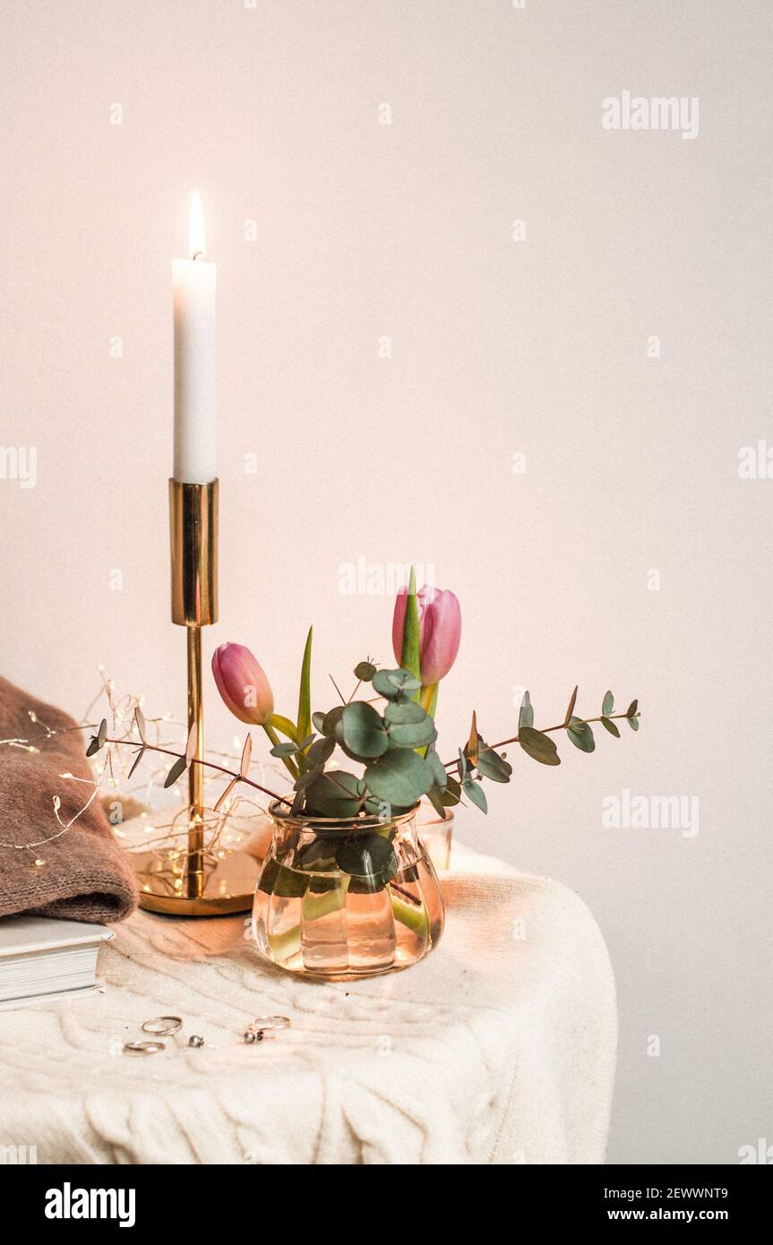 Heimatecke mit einem Buch, Kerzen, warmen Pullovern und Ringen, einem Strauß. Stockfoto