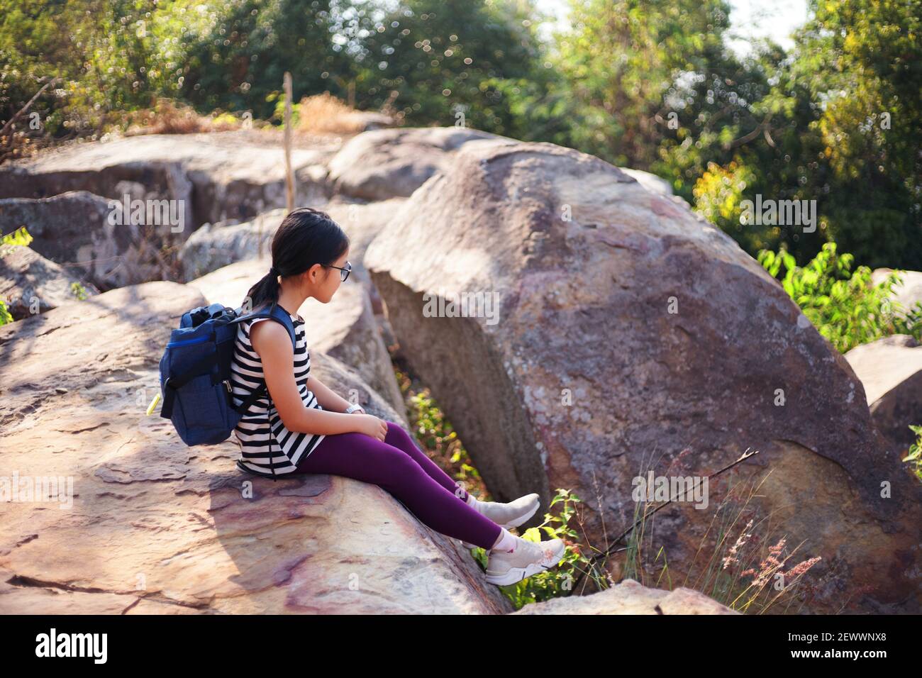 Ein Mädchen, das sich während einer Wanderung am Wochenende auf einem großen Felsen ausruhte Stockfoto