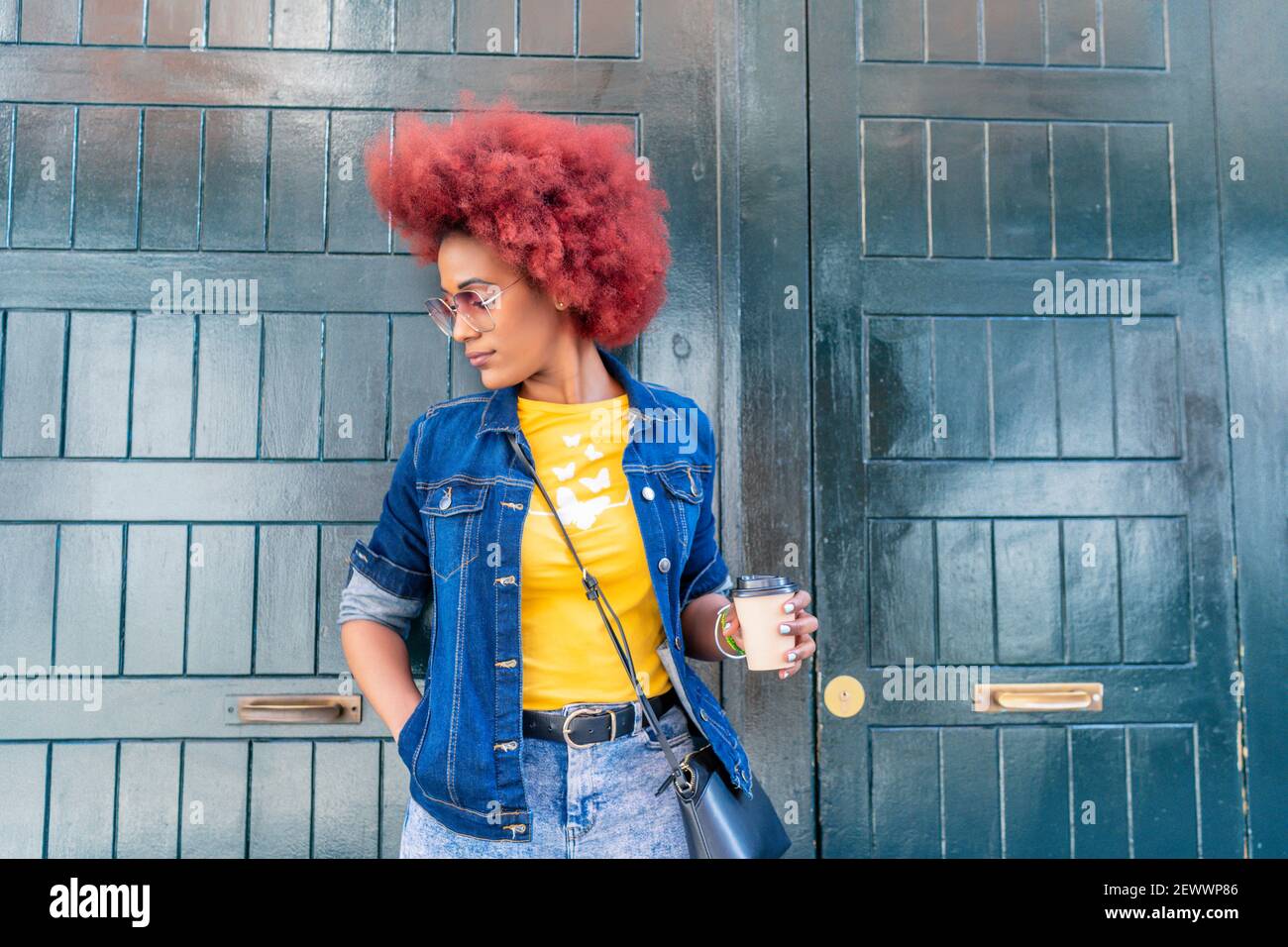 Frau mit roten Afro-Haaren mit ihrem Kaffee in der Straße Stockfoto