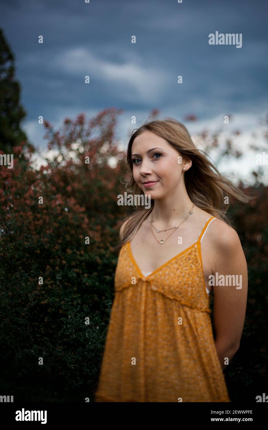 Eine junge Frau in einem Kleid steht zwischen blühenden Sträuchern Mit den Blue Ridge Mountains im Hintergrund Stockfoto