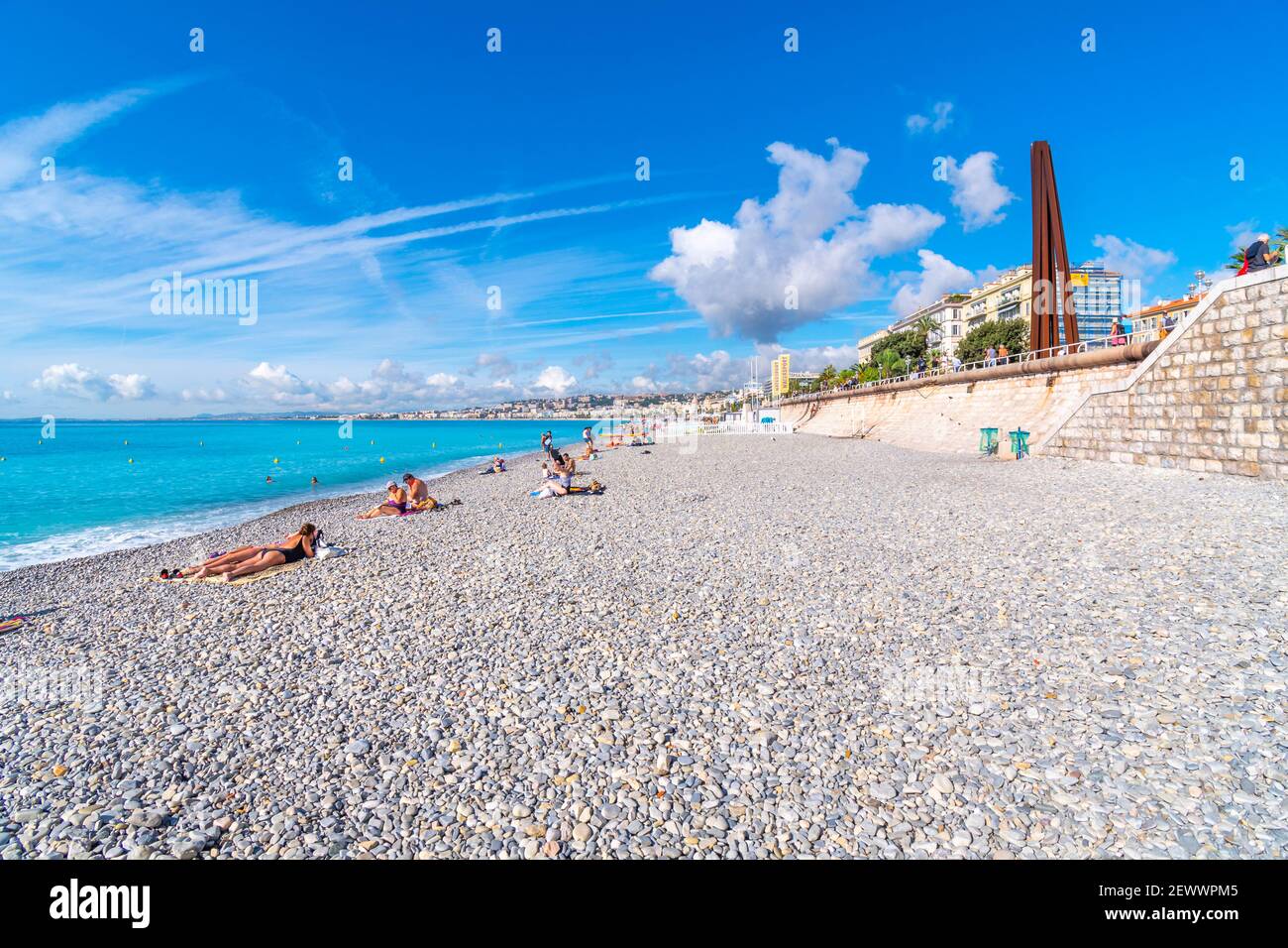 Touristen entspannen sich an einem Sommertag am Kiesstrand in der Bucht der Engel an der französischen Riviera in Nizza, Frankreich. Stockfoto