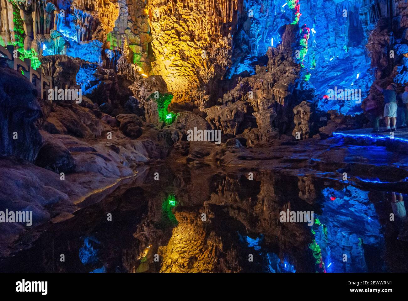 Guilin, China - 11. Mai 2010: Ludi Lu oder Reed Flute Cave. Blau beleuchteter Abschnitt der Grotte mit Stalaktiten und Stalagmiten. Reflektierender Teich vor. Stockfoto