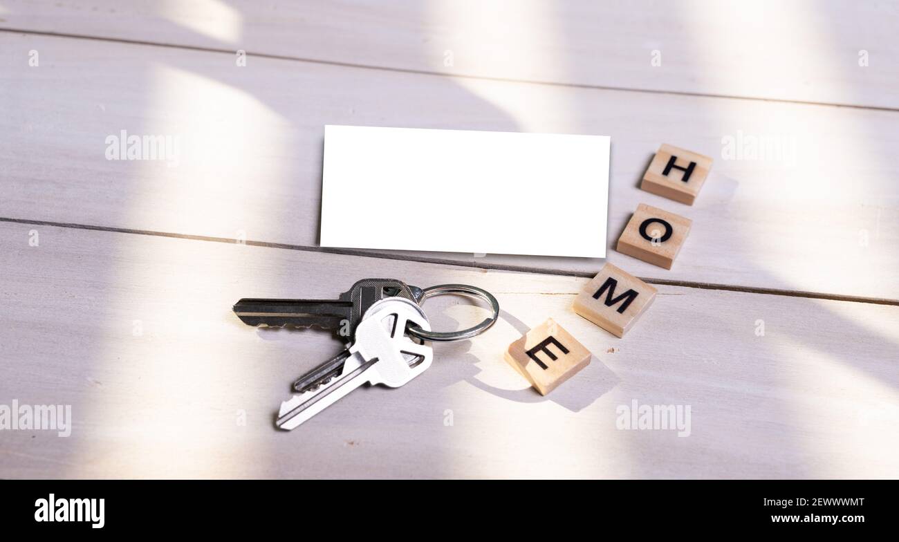 Modell, leere Visitenkarte und Heimschild mit Schlüsseln auf Holzhintergrund. Immobilienkonzept. Draufsicht. Stockfoto