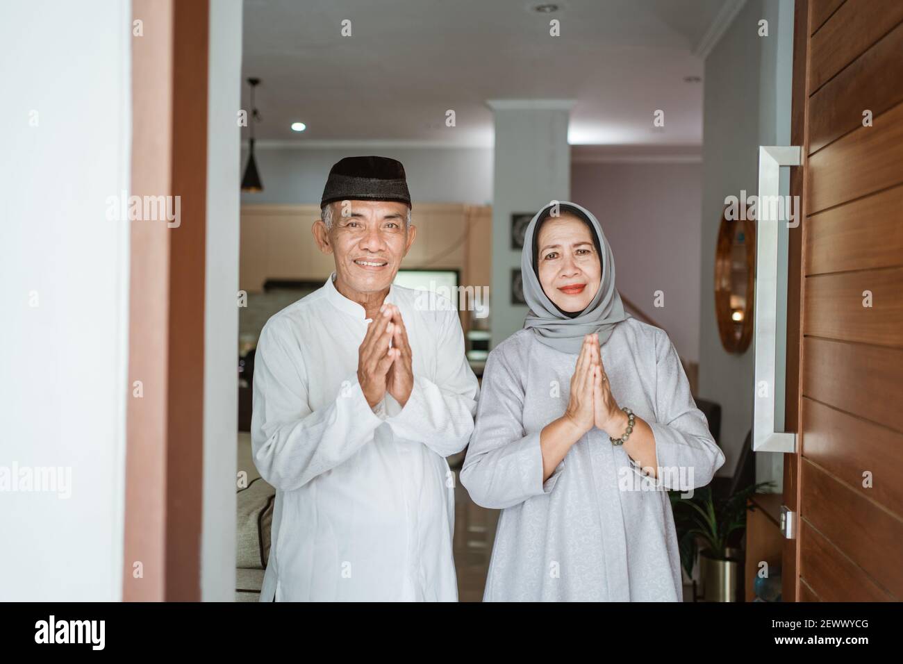 Portrait eines muslimischen asiatischen älteren Ehepaares, das vor der Haustür steht Warten auf Familie zu kommen Stockfoto