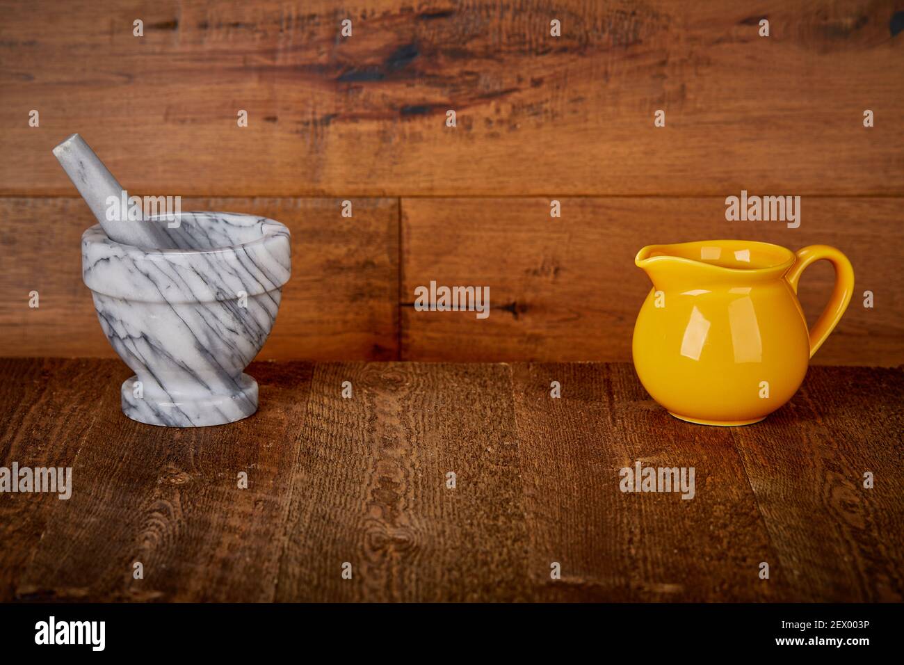 Kleine gelbe Keramik Krug Gießen Krug und Marmor Stein Mörser Und Stößelschleifer Brecher auf Old Barn Holzboden und Wand Hintergrund Aufnahme Oberfläche Stockfoto