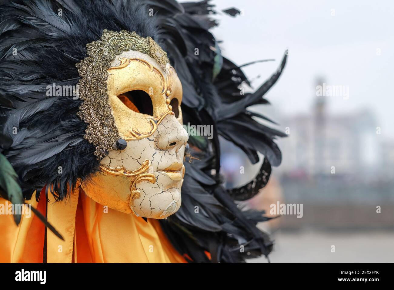 Venezianische Maskenmaske, Karnevalsmaske zum Verkauf in Venedig, Italien. Knisternde Gesichtsmaske aus Porzellan, umgeben von einer Wolke aus schwarzen Federn Stockfoto