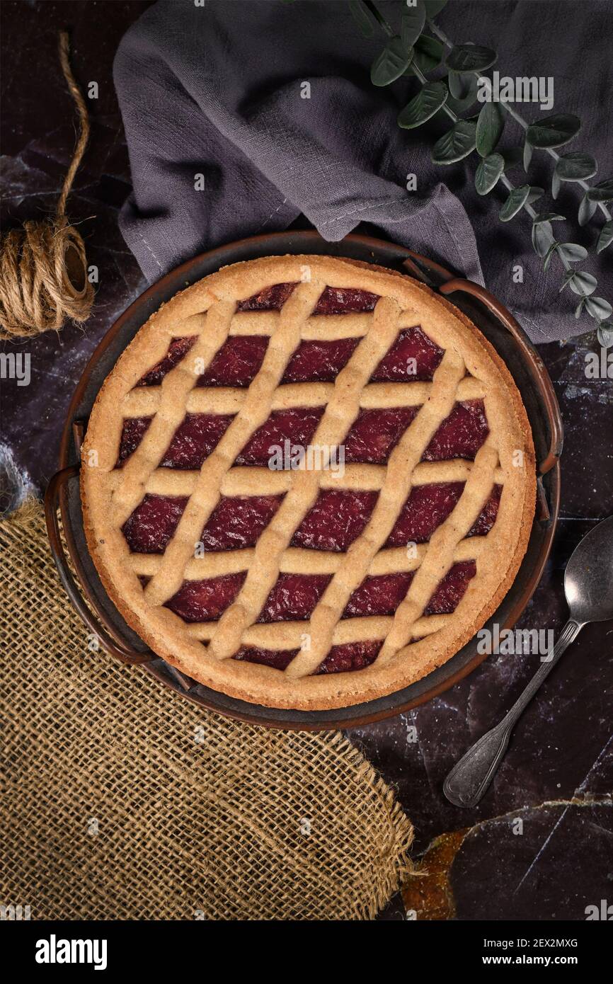 Draufsicht auf hausgemachten Kuchen namens "Linzer Torte", ein traditionelles österreichisches Shortcake-Gebäck mit Obstkonserven und in Scheiben geschnittenen Nüssen mit Gitterdessig gekrönt Stockfoto